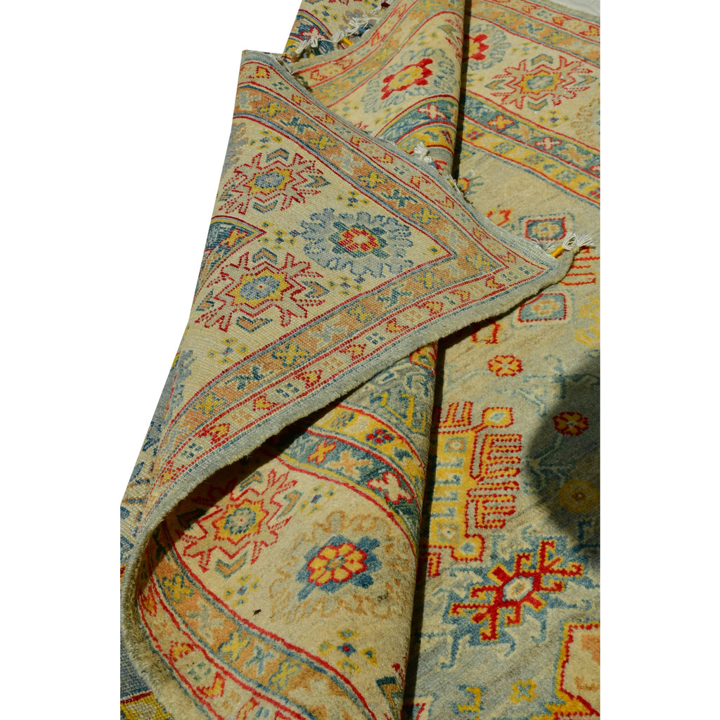 Handmade Afghan Aqcha Wool Rug 5x8 ft partially rolled view showing pile thickness and ivory fringe